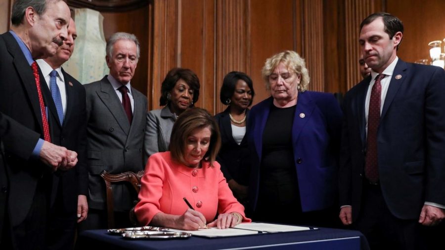  House Speaker Nancy Pelosi signs the articles of impeachment using  a set of commemorative pens with her signature inscribed onto them.