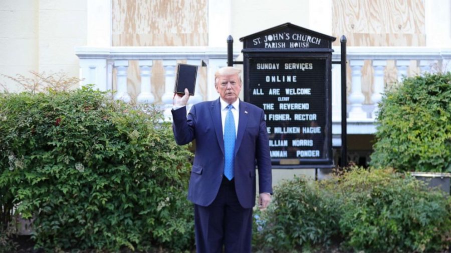 President Donald Trump holding the Holy Bible backwards and upside-down in front of a church he does not go to.