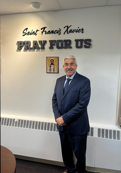 President Misenti Poses for a picture alongside a portrait of Saint Francis Xavier after being promoted to full-time president from his previous position as interim.